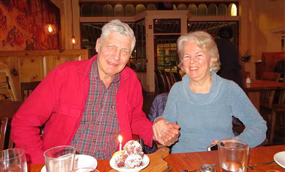 An older couple, husband and wife, hold hands at a restaurant.