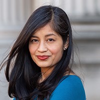 Headshot of a woman with long dark hair in a medium blue top