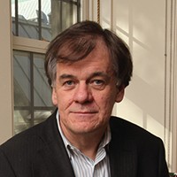 Headshot of a man with short dark hair in a suit and light-colored shirt