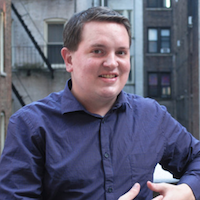 A headshot of a man wearing a dark shirt