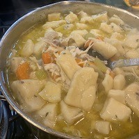 A pot of soup with carrots, chicken and dumplings