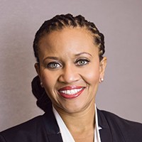 Headshot of a woman with dark hair pulled back, in a dark suit and white shirt.