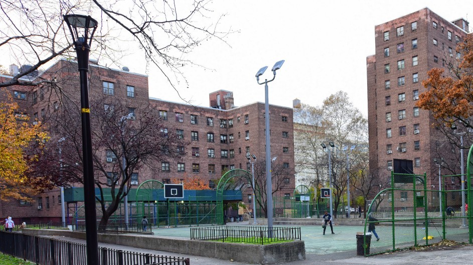 An image of a public housing building with kids playing basketball 