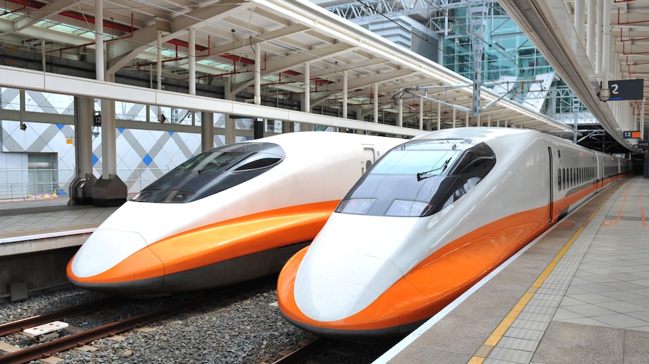 An image of two bullet trains that are white and orange in a train station in Taipei