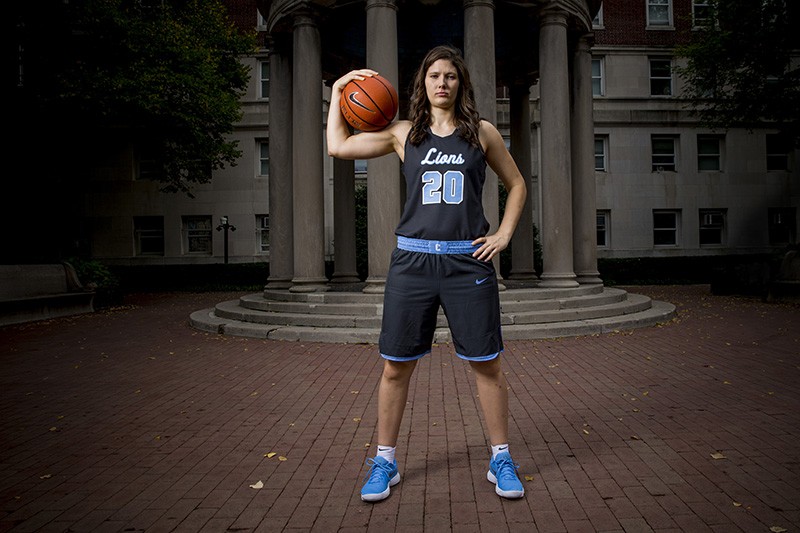 Camille Zimmerman poses with basketball in her uniform in front of a gazebo