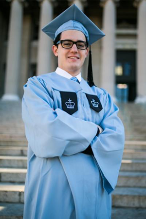 Mounir Ennenbach in cap and gown, with his arms crossed