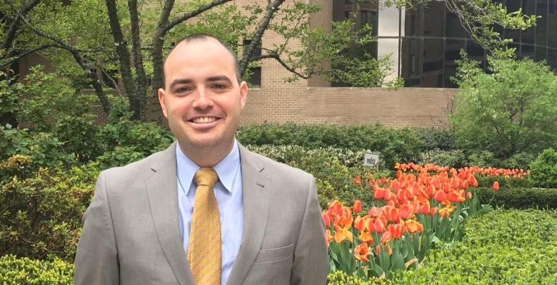 Paul Coyne in a suit in tie, in front of a garden