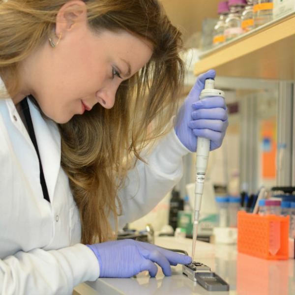 Researcher Sophie Zaaijer uses the MinION, a portable DNA sequencer, to get a quick genetic readout of a sample of cells. (New York Genome Center) Researcher in lab