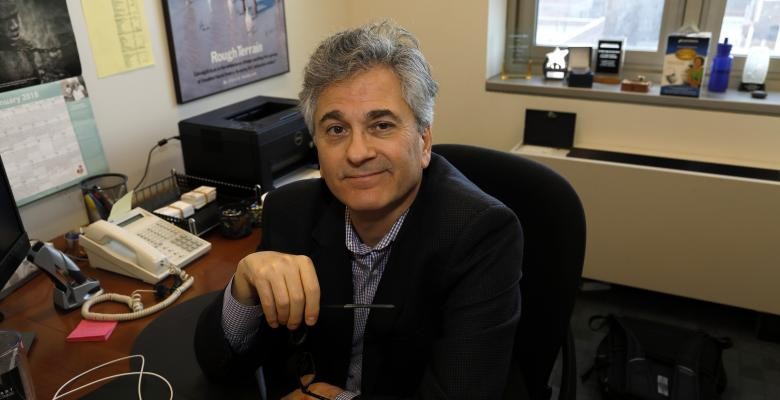 Photo by John Pinderhughes Vincent Schiraldi sits at his desk and holds a pair of glasses