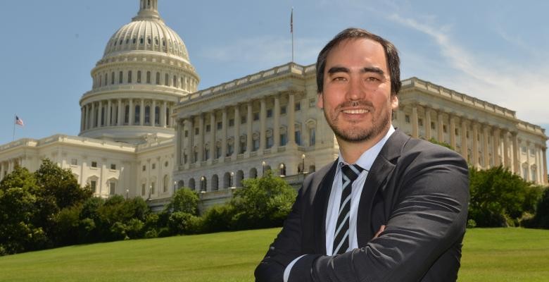 A man with arms crossed stands in front of Congress