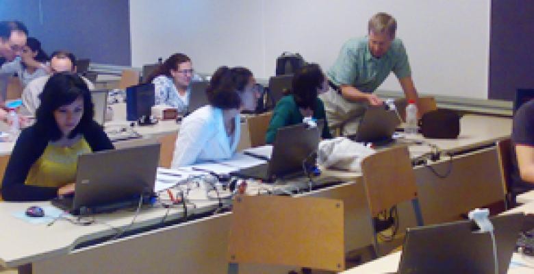 John Huber works with a student during a daily lab session in Cairo. Huber arranged for students to work with "Stata," a sophisticated software tool applied quantitatively to political science research questions. Classroom with desks and students