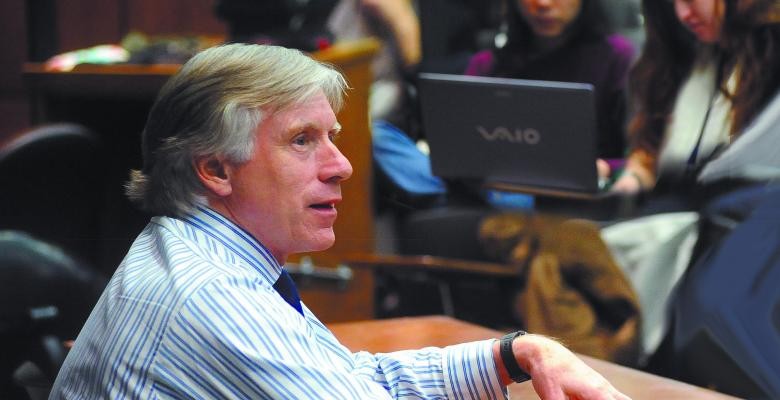 Profile image of Lee Bollinger wearing a light blue double striped shirt while speaking to somone off camera 