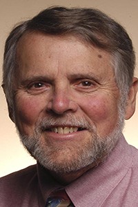 Mike Pride smiles directly into camera lens wearing a lavendar button down shirt