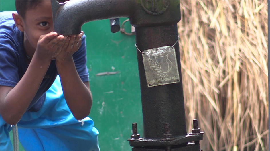 A boy drinks clean water from a pump.