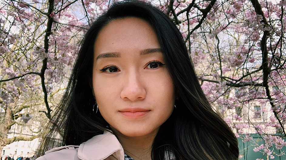 Asian woman with long black hair with cherry blossoms behind her