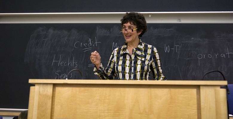 carol sanger stands behind podium speaking