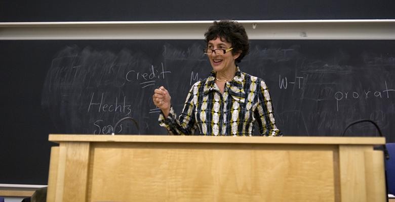 carol sanger stands behind podium speaking