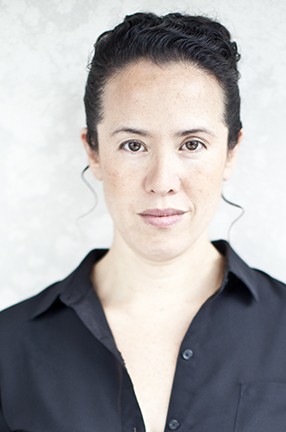 A woman with dark hair wearing a dark buttoned shirt.