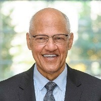 Wilmot James: A bald, bespectacled man, wearing a suit and tie, smiling into the camera.