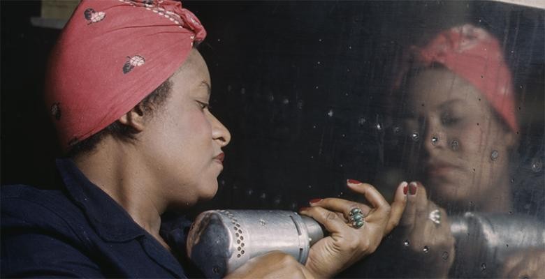 woman wearing a red bandana uses a powerdrill while working 