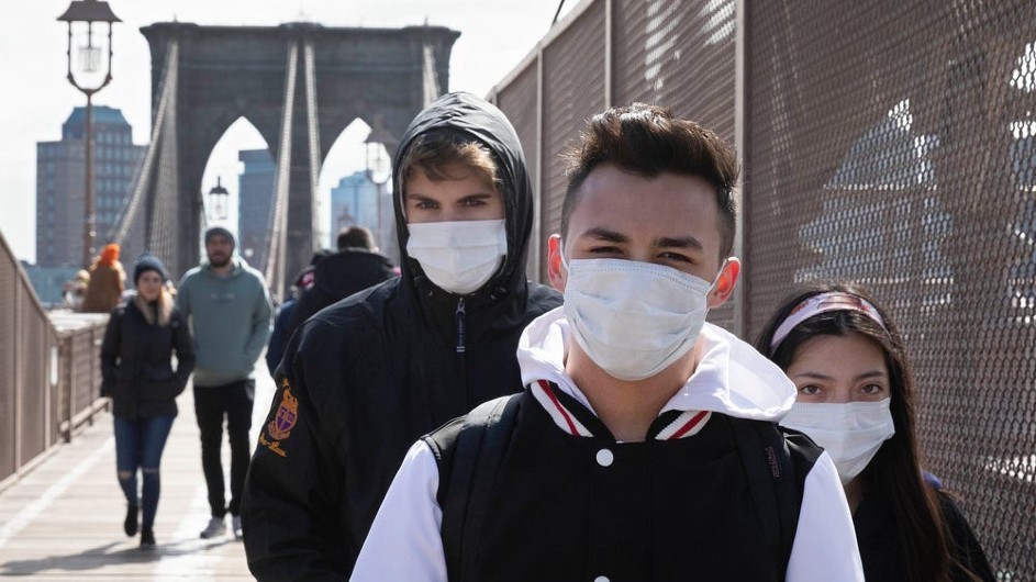 Young people wearing masks cross the Brooklyn Bridge. AP Photo/Mark Lennihan Masked young people crossing a bridge