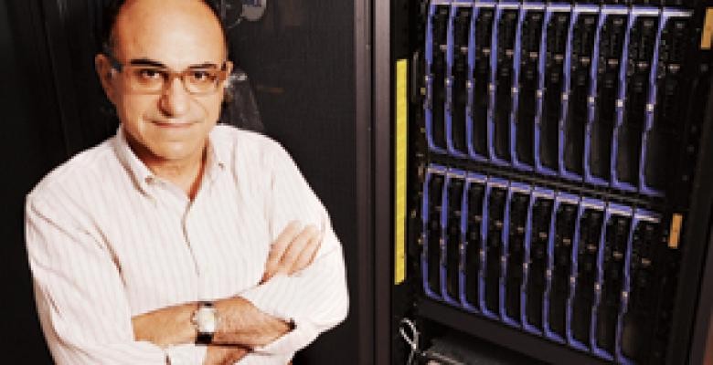 Professor Dimitris Anastassiou stands next to a high-performance computer cluster that was instrumental for his latest research in cancer biology. Image credit: Eileen Barroso/Columbia University