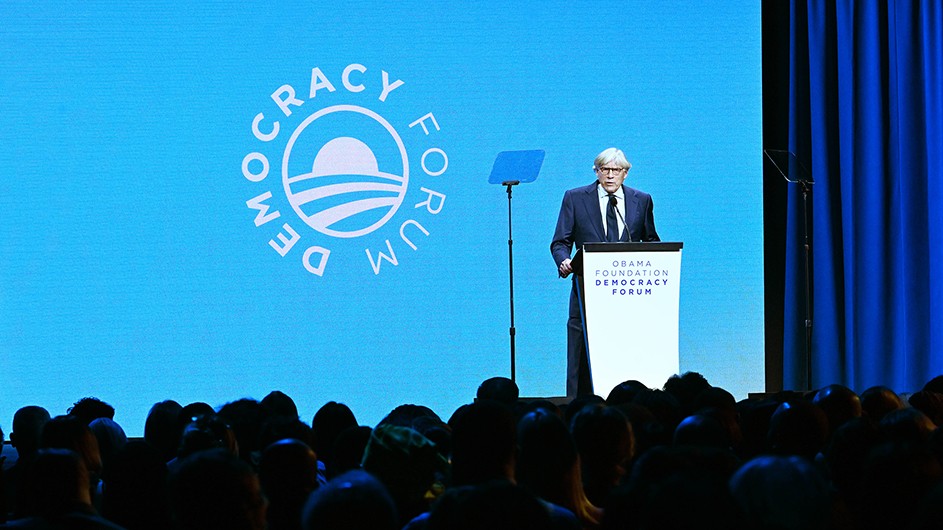 Columbia President Lee C. Bollinger speaks at a podium on stage in front of dozens of spectators at the Obama Foundation Democracy Forum.