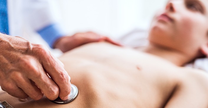 Doctor examines young boy's gastrointestinal area.