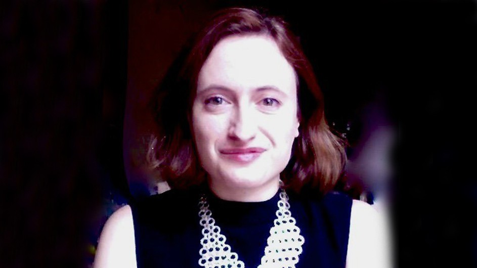 A woman wears  sleeveless black top and a silver necklace.