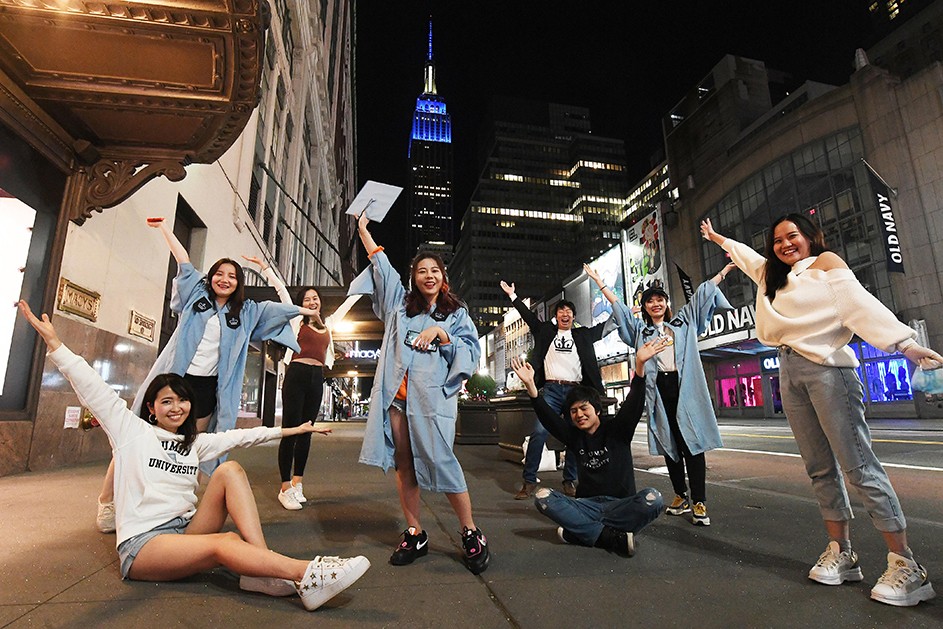 Photo by Eileen Barroso/Columbia University. The Empire State Building image ® is a registered trademark of ESRT Empire State Building, L.L.C. and is used with permission. A group of friends poses at 34th Street and 7th Avenue with the Empire State Building.