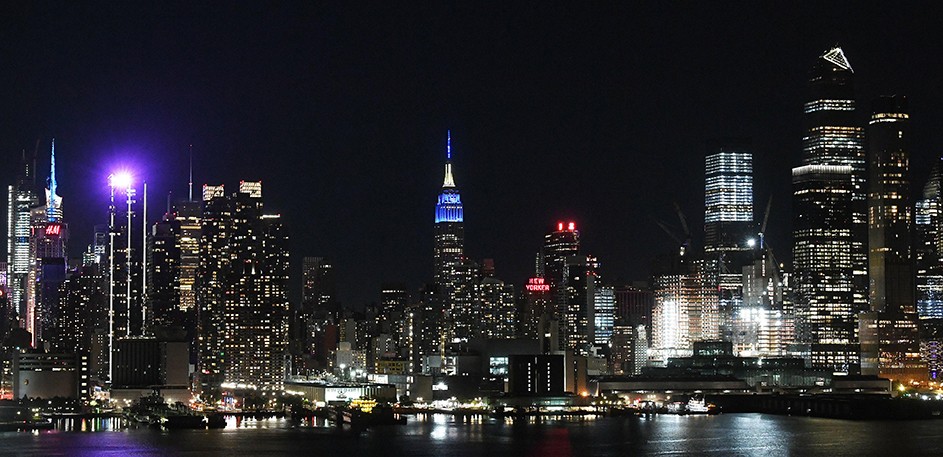 The New York City skyline as seen from New Jersey with the Empire State Building lit blue.