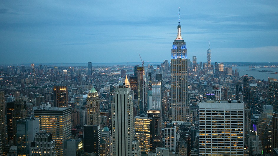 The Empire State Building from above in a light blue sky. 