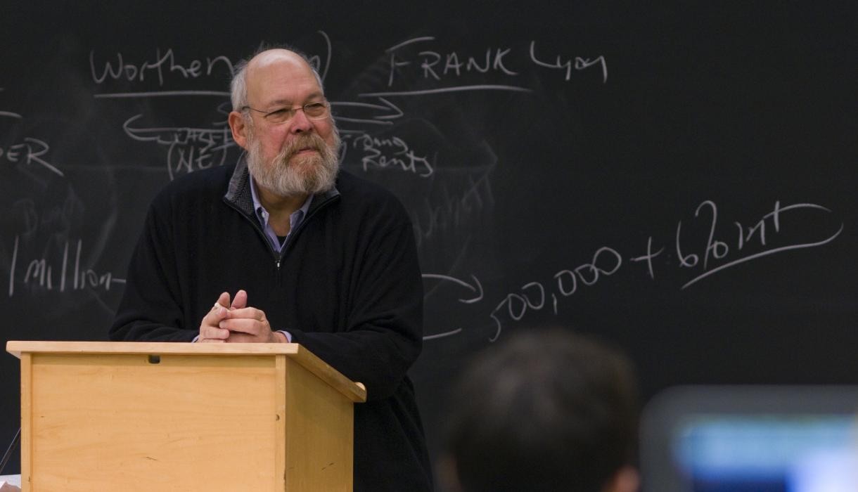 Professor Michael Graetz co-wrote his new book, "The Wolf at the Door: The Menace of Economic Insecurity and How to Fight It," with Yale Professor Ian Shapiro. A man stands behind a lectern and in front of a blackboard.