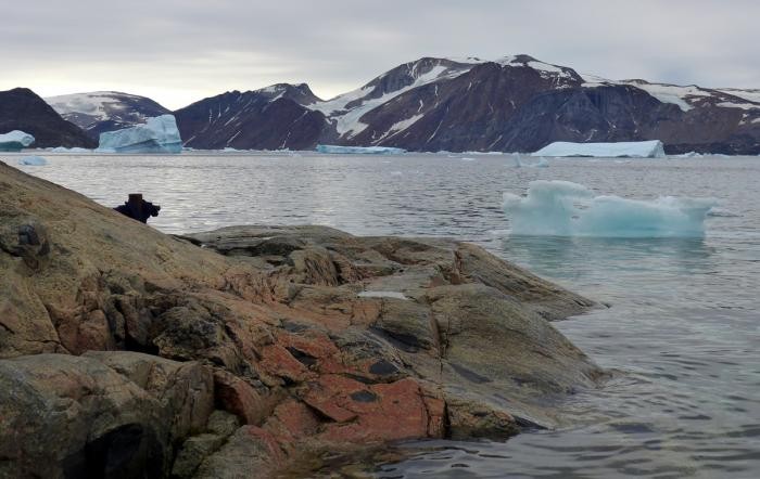 view of rocks extended into the ocean with smaller pieces of ice mountains floating