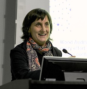 Laura Kurgan: A woman wearing a colorful scarf speaking at a lectern.
