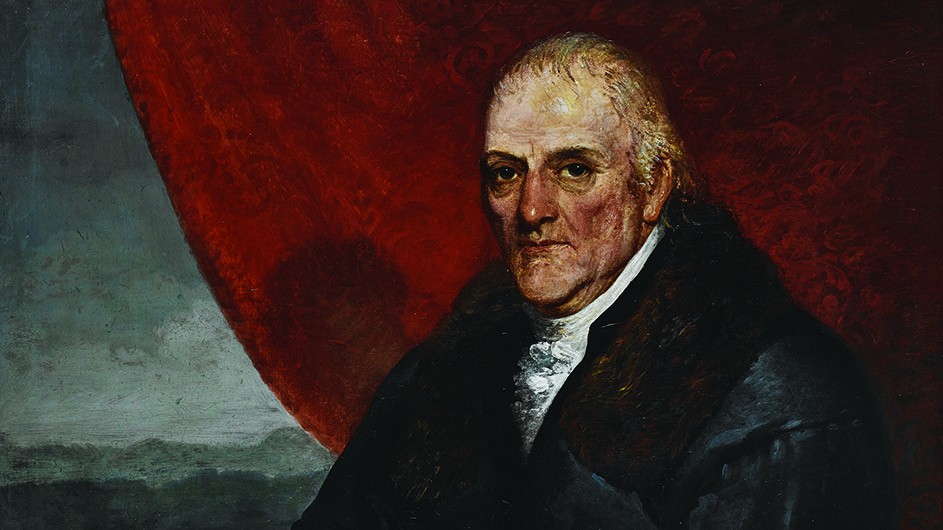 Avery Architectural and Fine Arts Library, Columbia University A painting of a man wearing a dark coat over a white shirt and seated against a rust-red curtain backdrop.