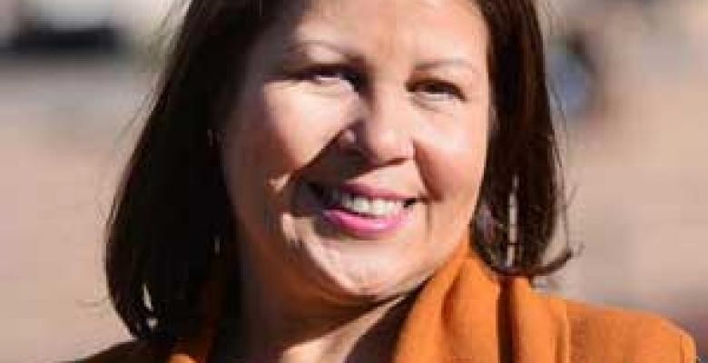 An outdoor closely cropped image of Marah Arbaje smiles into camera wearing an apricot colored top