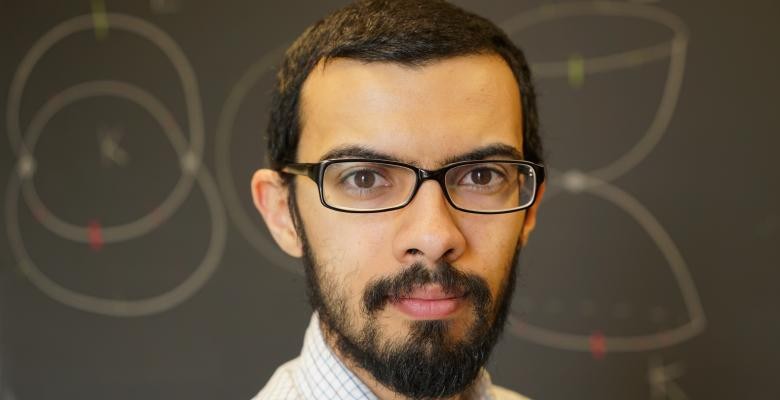 Columbia Mathematics Professor Mohammed Abouzaid wears dark rimmed eyeglasses dark facial hair covers jawline while he looks directly into camera