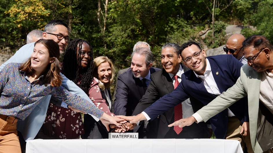 Participants in Friday's event in Morningside Park gather to ceremonially hit a button to turn Morningside Park's waterfall on.