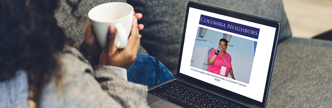 A woman sips coffee while reading Columbia Neighbors newsletter. 