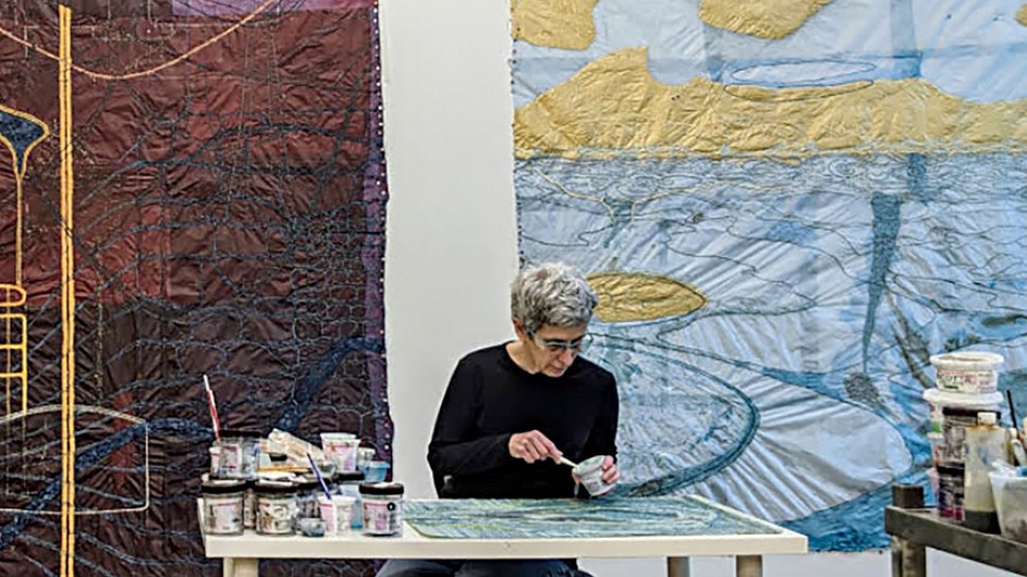 Nancy Cohen with "13A" (left) and "Espiritu Santo," two drawings influenced by the pandemic. (Courtesy of Nancy Cohen) Nancy Cohen: A woman works at a table in front of artworks on a wall.