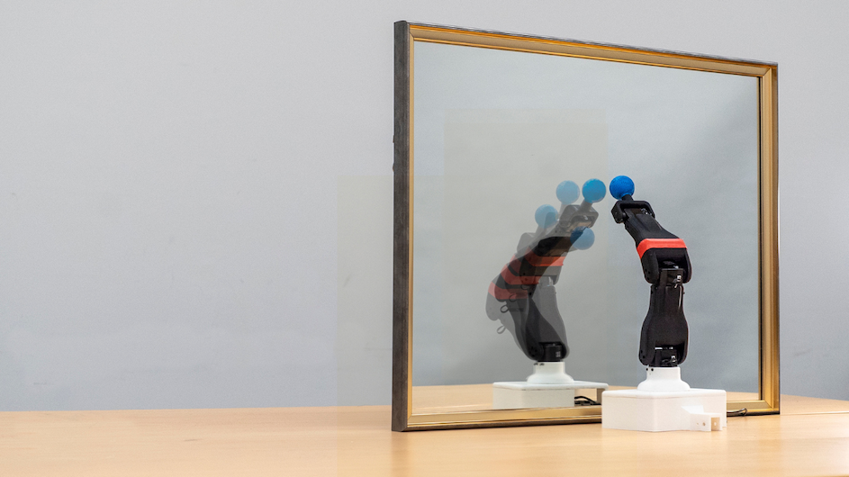 A robot observes its reflection in a mirror.