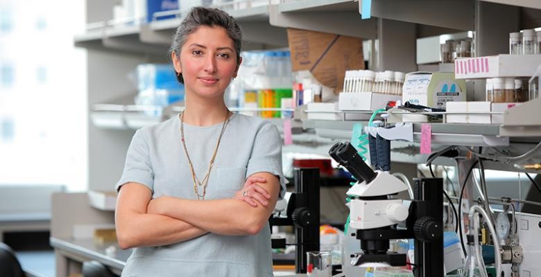 Rudy Behnia stands in research lab wearing a grey top and arms folded