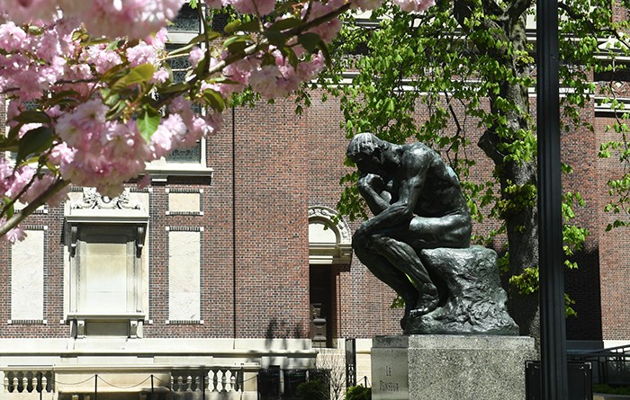 The Thinker sculpture between Magnolia flowers. 