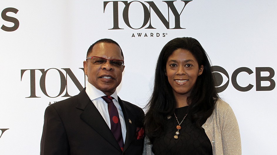 Stephen Byrd and Alia Jones-Harvey A couple dressed in elegant clothes smile for the camera before a backdrop for the Tony Awards.