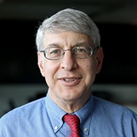 Thomas Kent: A man with gray hair, eyeglasses, wearing a blue shirt and red tie.