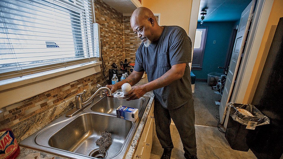 Communities of color are likelier to have poor water quality, according to a new study. (Mari Maloney) A man stands by a sink with a water filter.