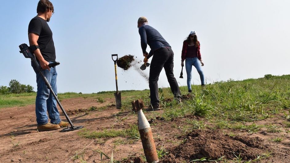 At an experimental explosives range in Oklahoma, a team searches for buried ordnance. Foreground, an unexploded U.S.-made M6A1 antitank rocket. All weapons shown in this story have been disarmed. (Kevin Krajick/Earth Institute)