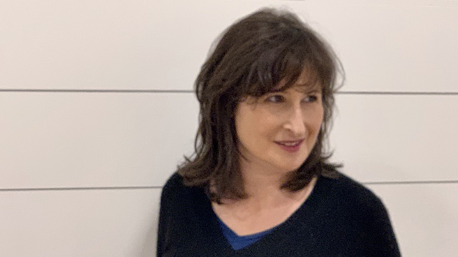 Victoria Rosner: A woman wearing a black shirt, standing against a white wall.