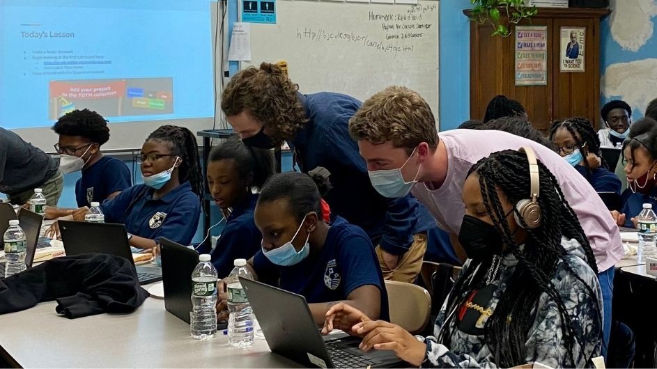 Columbia graduate students Samuel Moore (left) and Aaron Holman (right) review code on a recent day of tutoring at Democracy Prep. Columbia graduate students mingle with Democracy Prep Harlem High School students during Coding Club